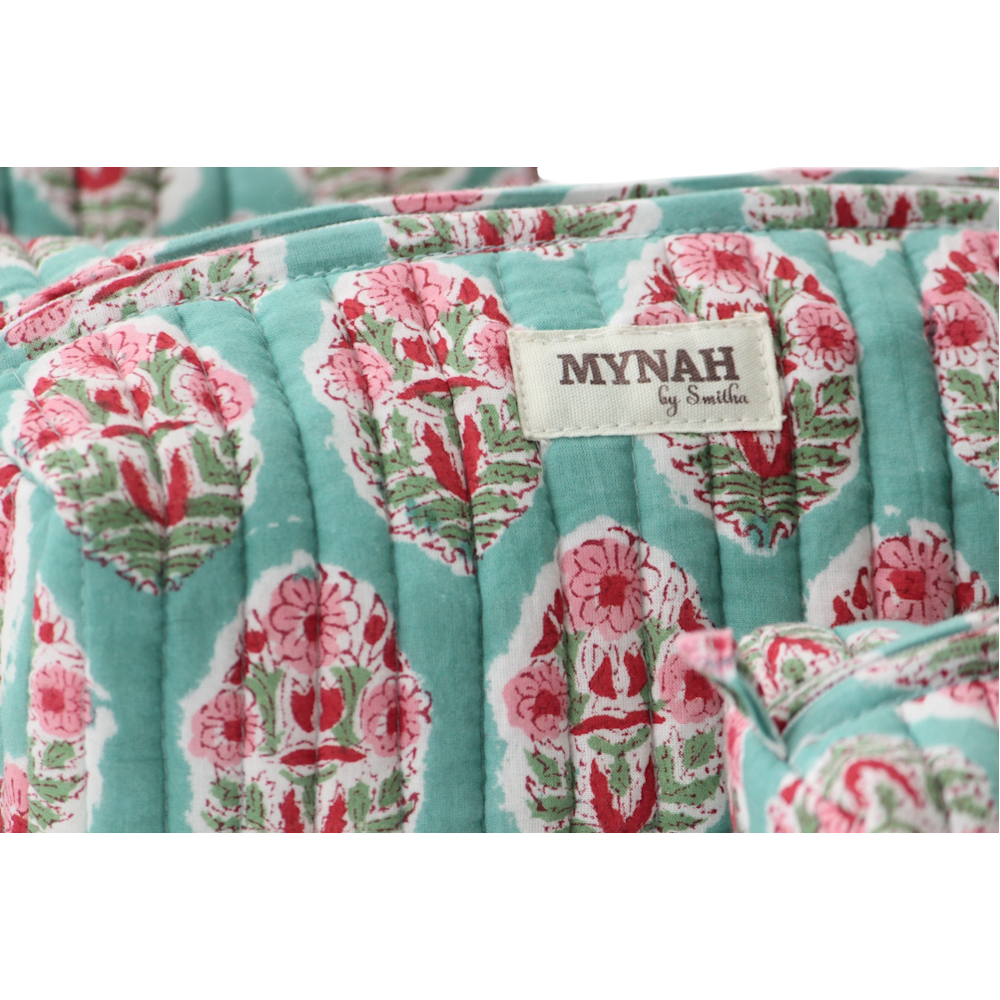 Quilted turquoise block print pouch with pink floral bouquets and a MYNAH by Smitha fabric label.