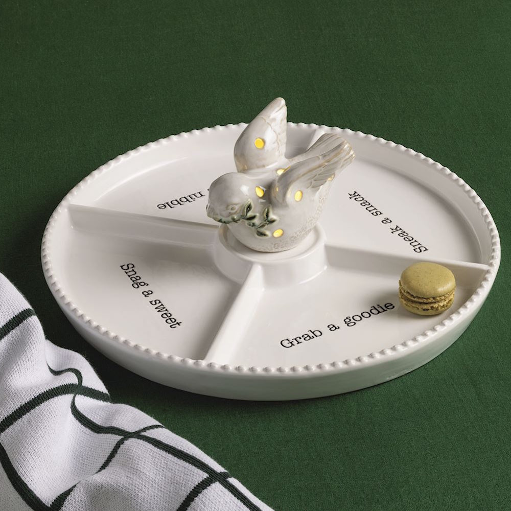 Light-up dove figurine on a white round serving tray with divided sections and a macaron.
