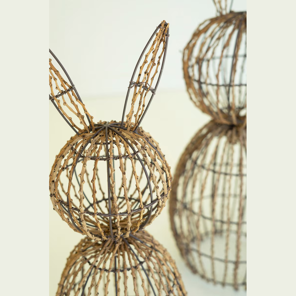 Two rustic rabbit figurines made of dark metal wire frames wrapped in natural brown twigs against a neutral background.