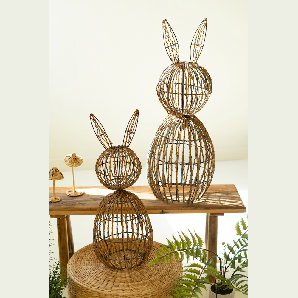 Two rustic twig and wire bunny sculptures in different sizes displayed on a wooden bench with natural spring decor.
