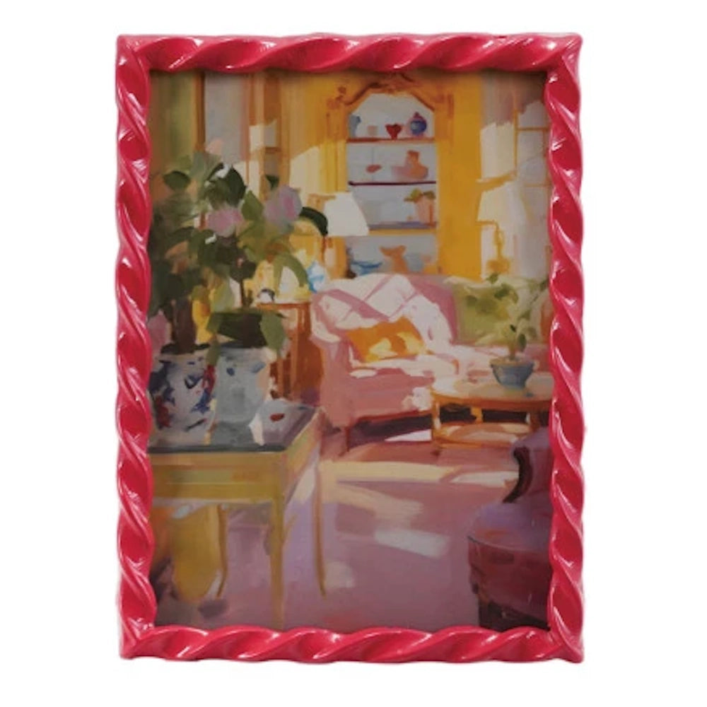Glossy pink twisted rope picture frame containing a painting of a sunlit interior with blue and white chinoiserie vases.