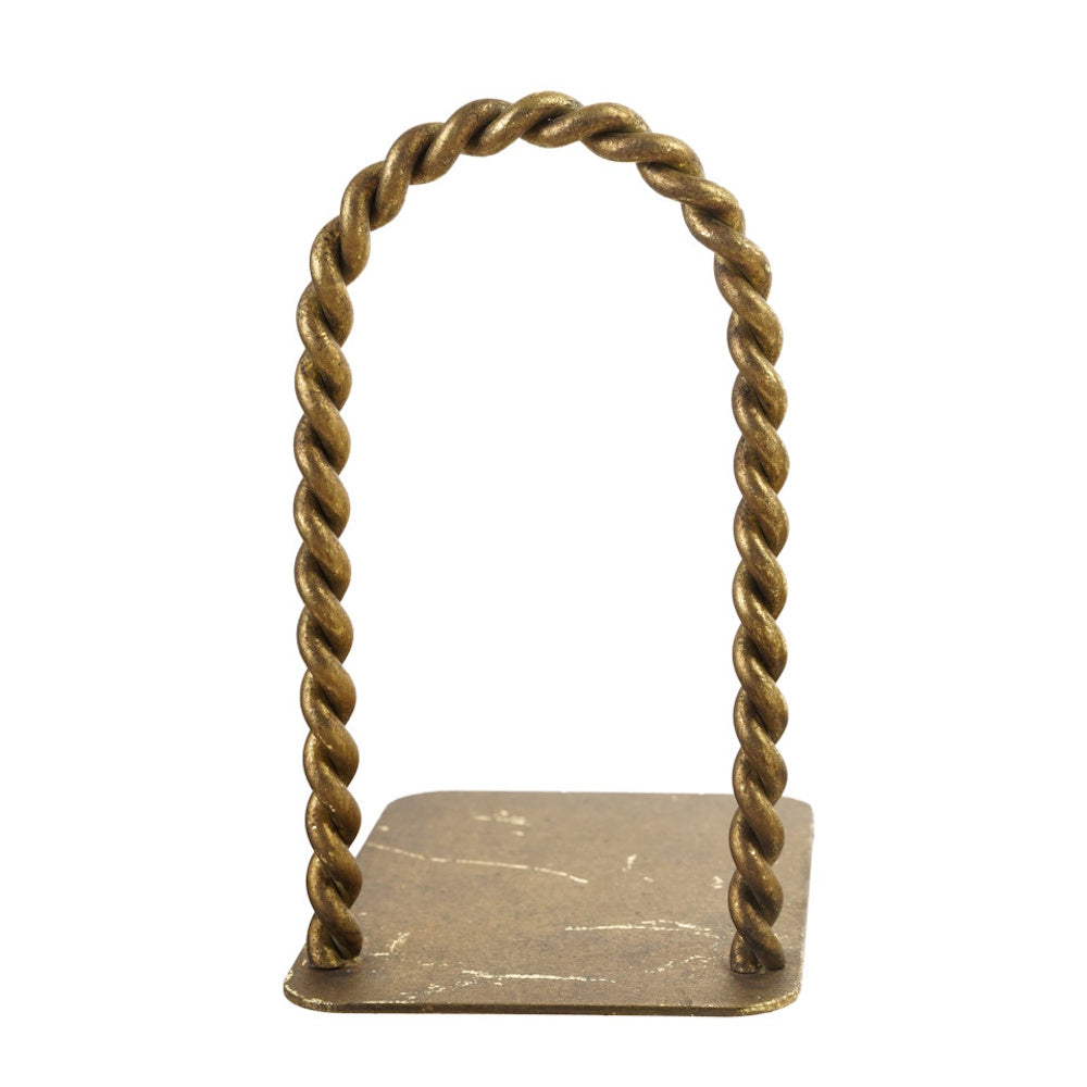 A single antique brass bookend featuring a thick, twisted metal arch attached to a flat rectangular base.