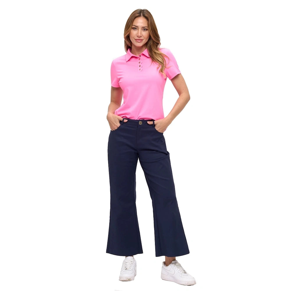Woman in navy wide-leg ankle pants and a pink polo shirt with white sneakers on a white background.