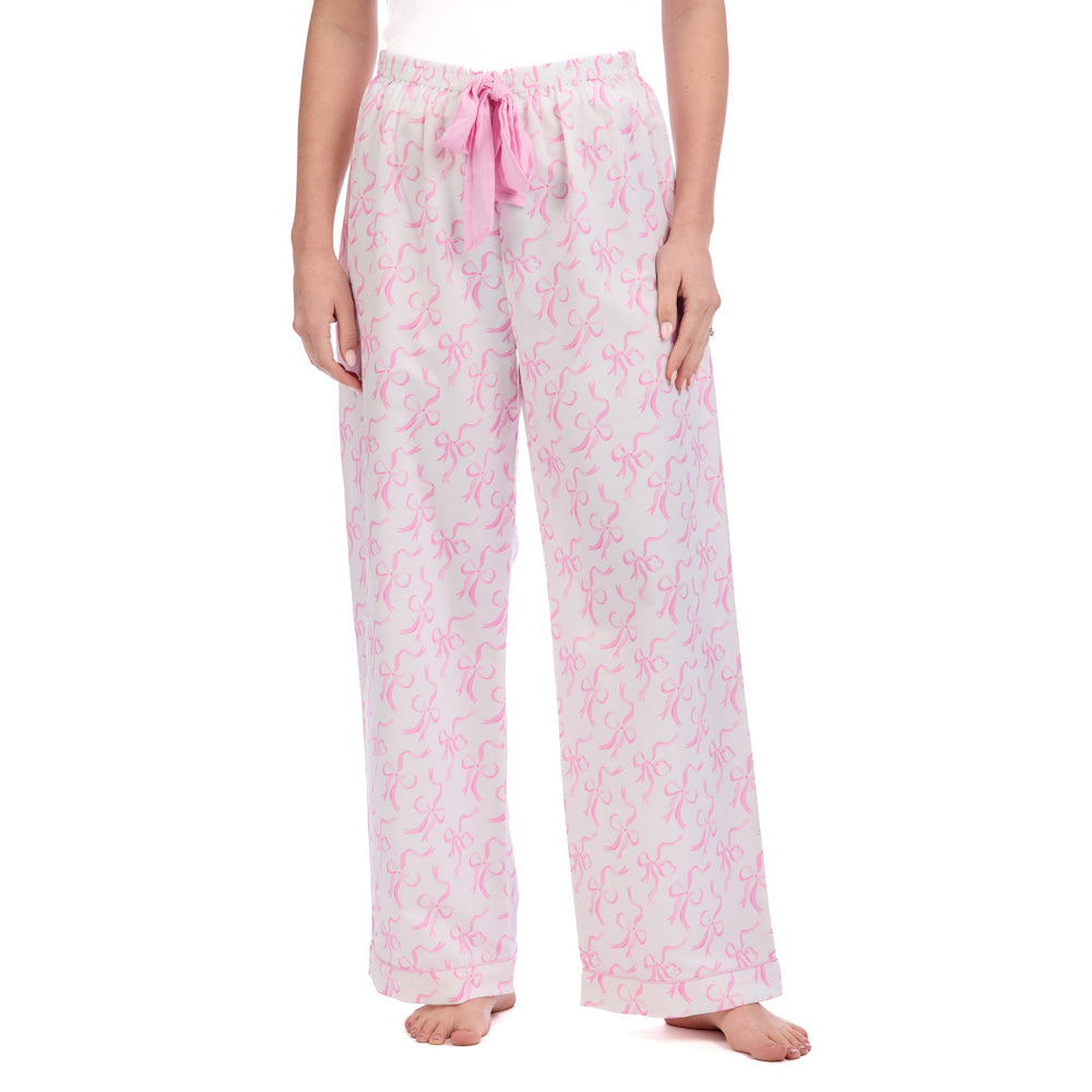 White pajama pants with a pink bow pattern, an elastic drawstring waistband, and a relaxed fit for Valentine's Day sleepwear.