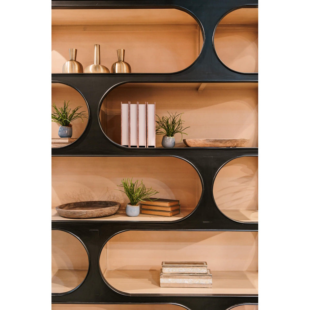 Modern Vannes crescent bookcase with black geometric frame, wooden shelves, and decorative home decor accents.