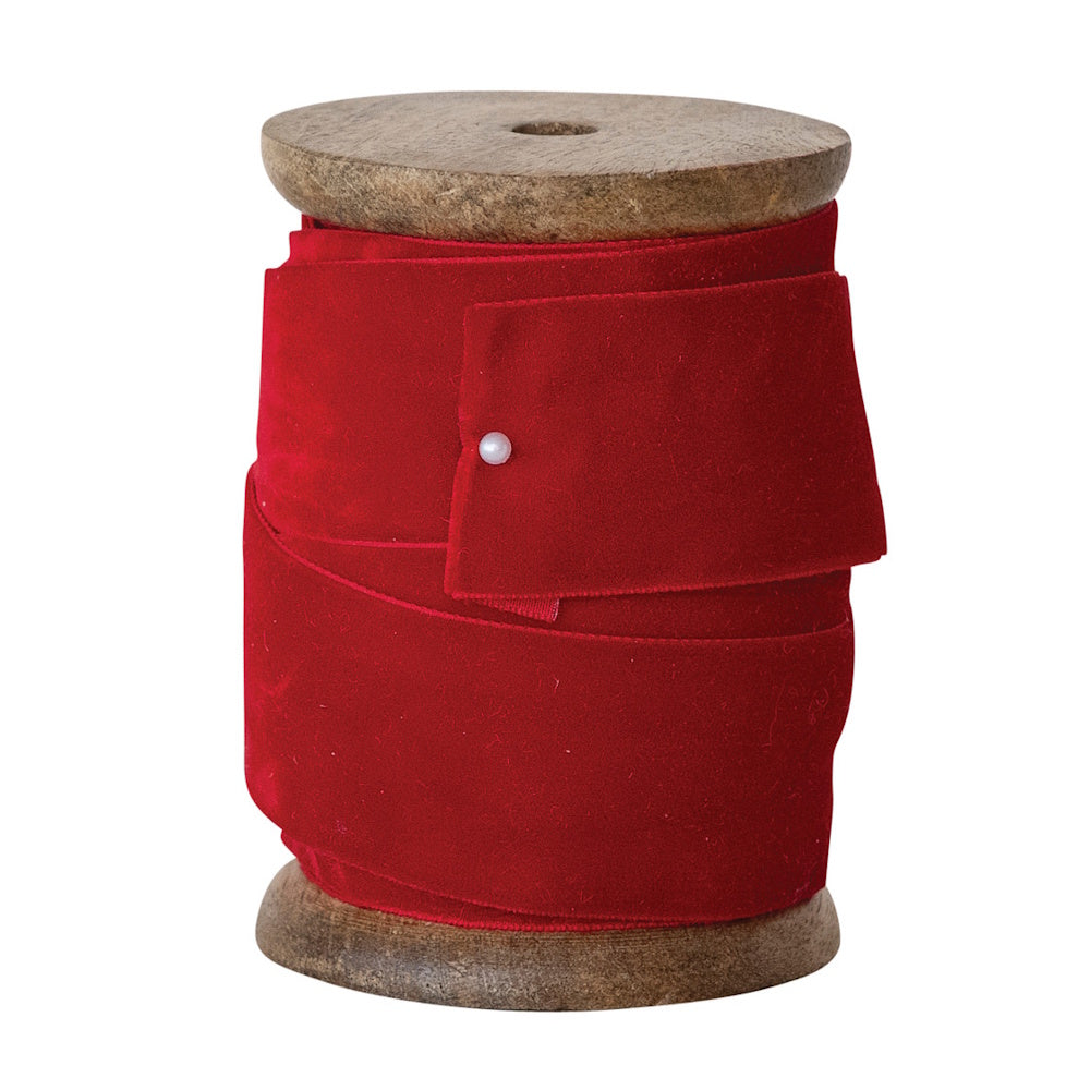 Red velvet ribbon wrapped around a wooden spool, secured with a pearl-headed pin.