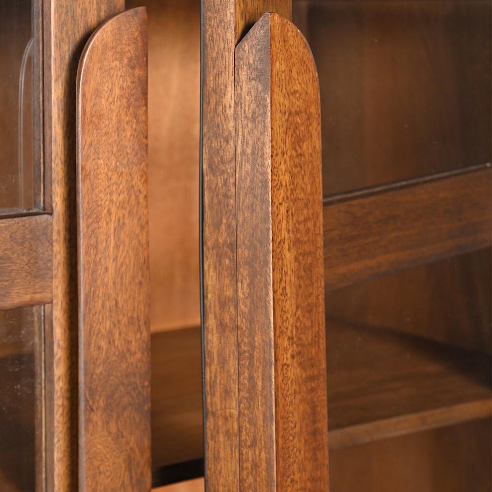 Close-up of mid-century modern walnut wood cabinet with arched handles and glass display doors.