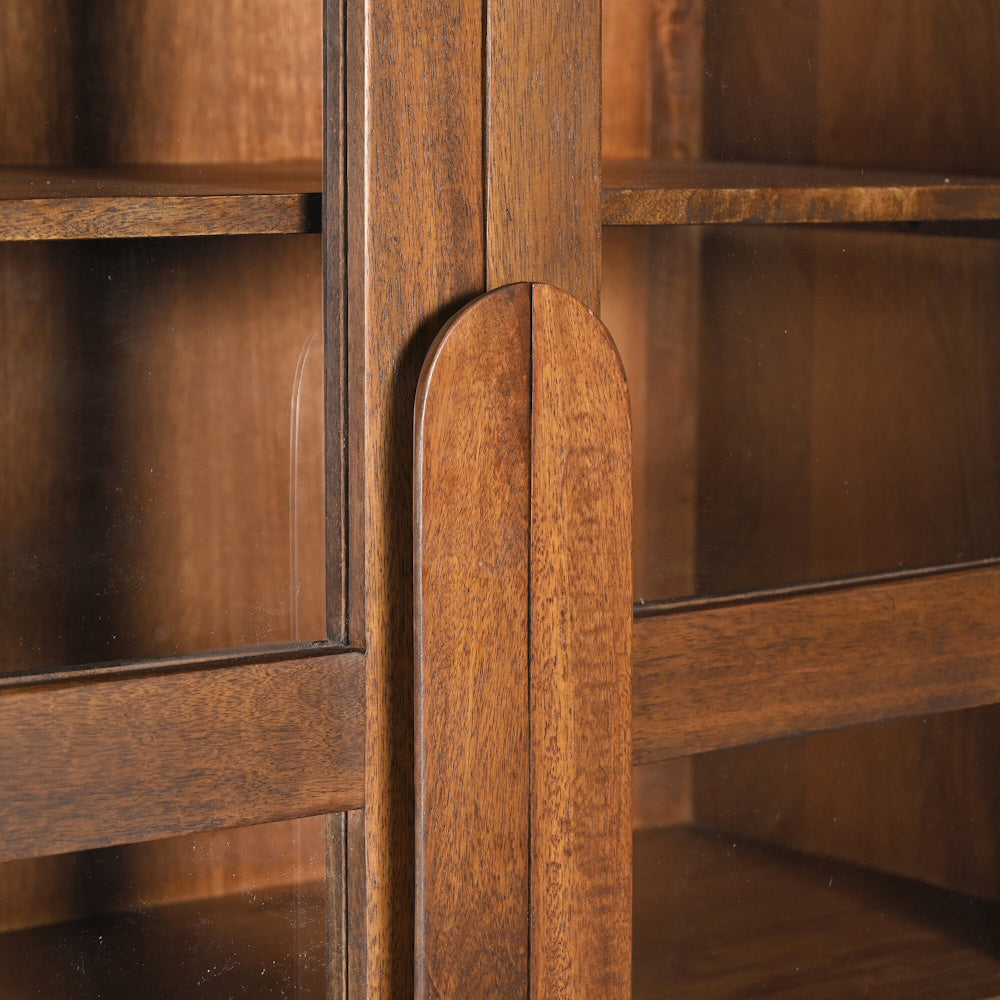 Close-up of a mid-century modern walnut display cabinet with glass doors and arched wooden handles.
