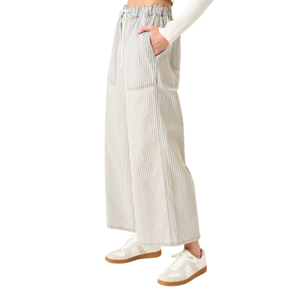 Side view of a person wearing striped wide-leg pants with a drawstring elastic waist and white sneakers.