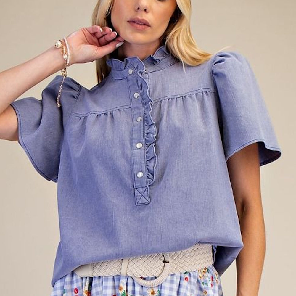 Front view of washed blue chambray top with ruffled collar, button placket, and flutter sleeves.