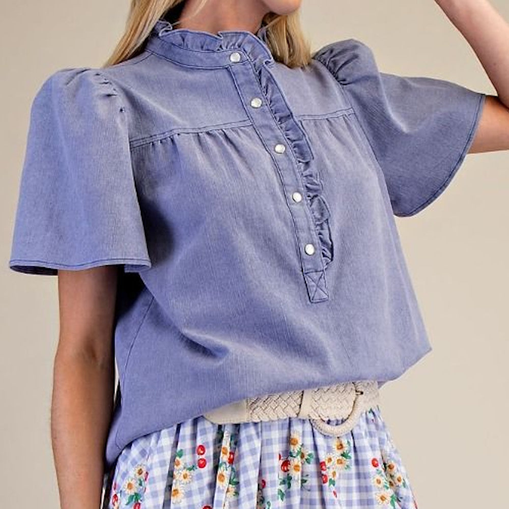 Side view of washed blue chambray top featuring flutter sleeves and ruffle-trimmed placket.