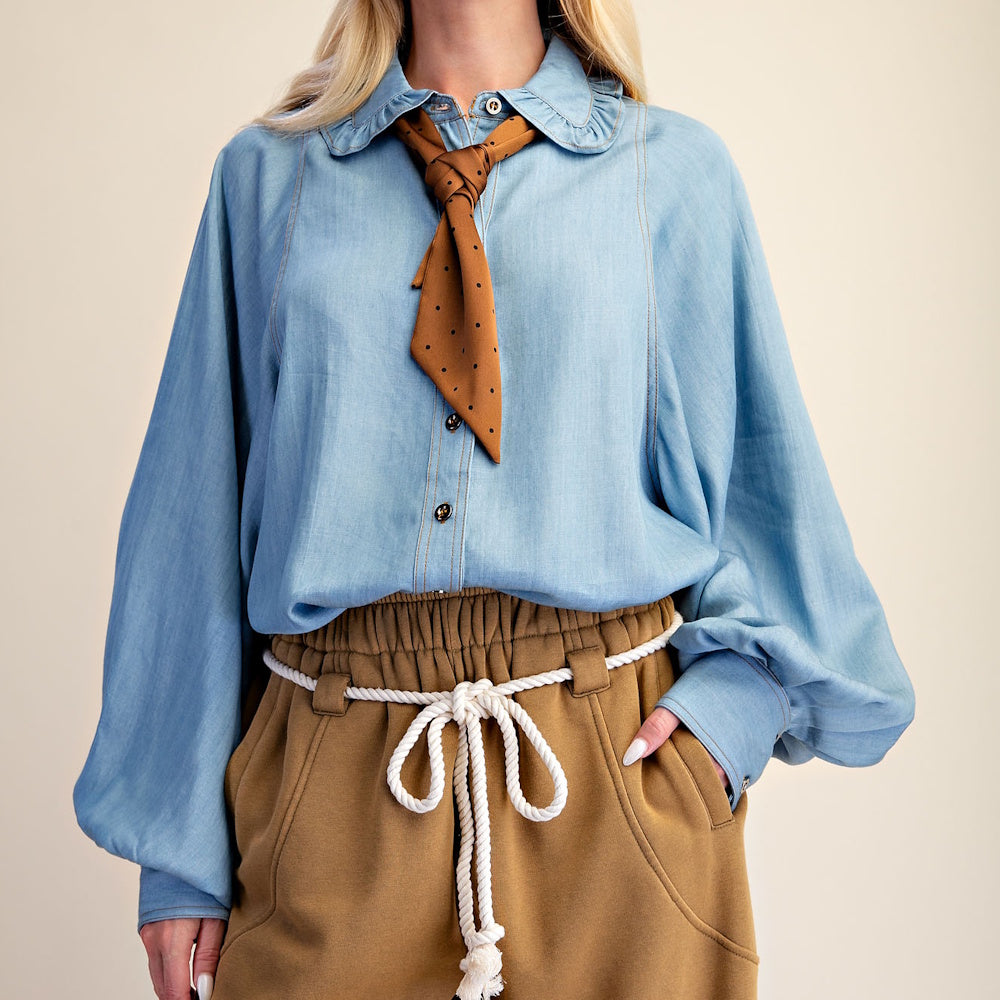 Front view of light blue washed denim chambray shirt tucked into tan pants with a rope belt.