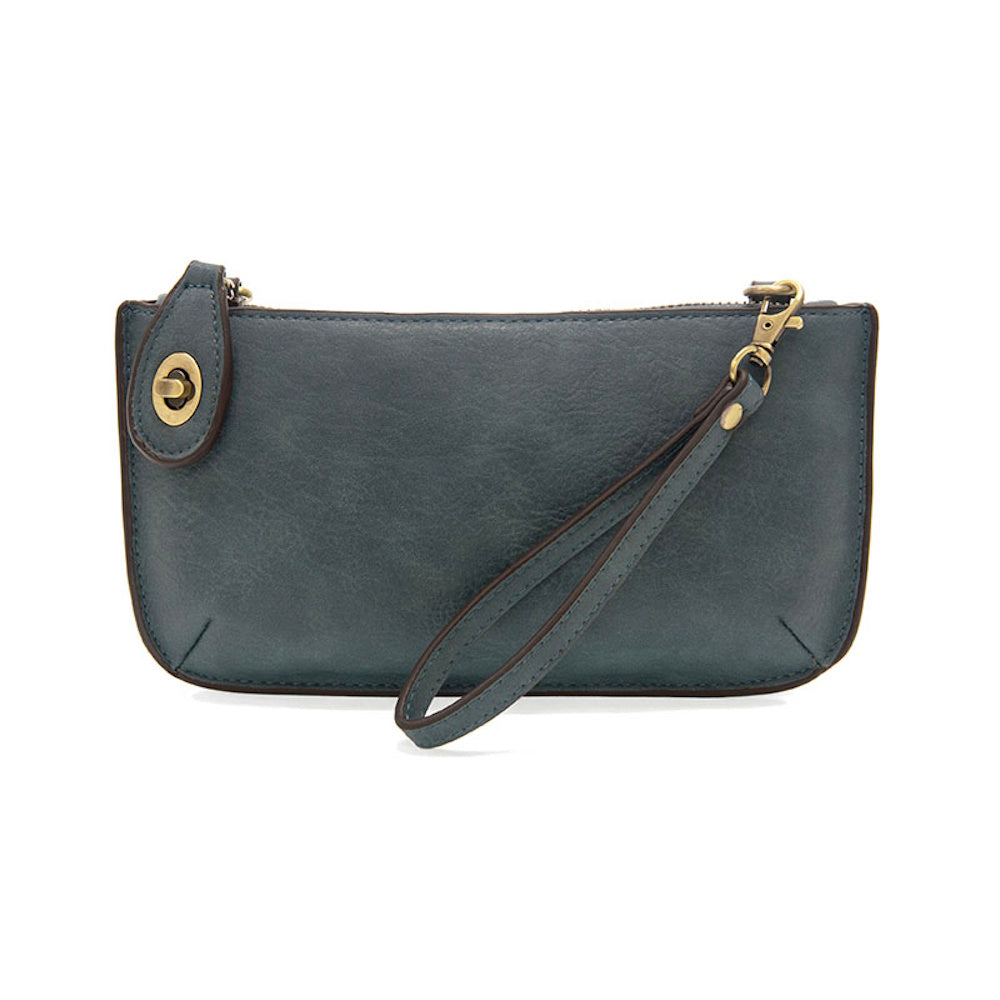Washed denim mini crossbody wristlet clutch with a top zipper, wrist strap, and brass hardware detail.