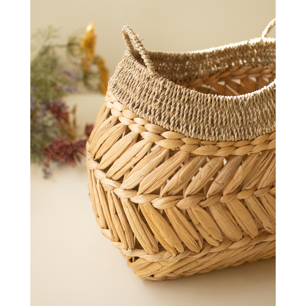 Close-up of a handwoven water hyacinth basket, highlighting its intricate chevron weave and handles.