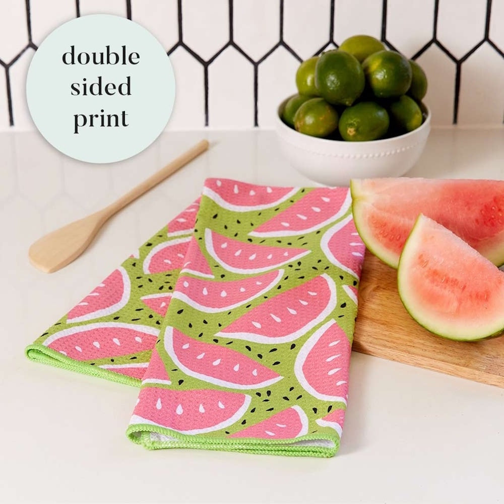 A green and pink watermelon pattern kitchen towel next to fresh watermelon slices and a bowl of limes.