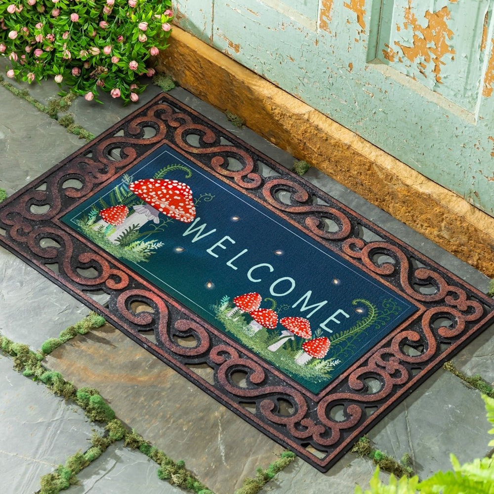 A doormat with a scrollwork border and "Welcome" text alongside red and white mushrooms.