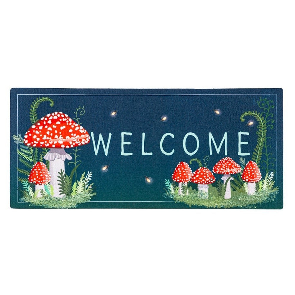 A dark blue doormat featuring red and white mushrooms, green ferns, and the light blue word "WELCOME".