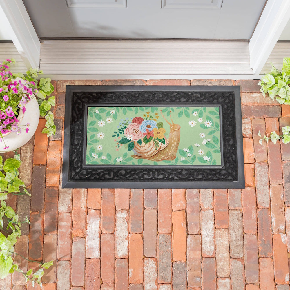 Snail garden doormat featuring a floral shell and green leaf background on a brick entryway.