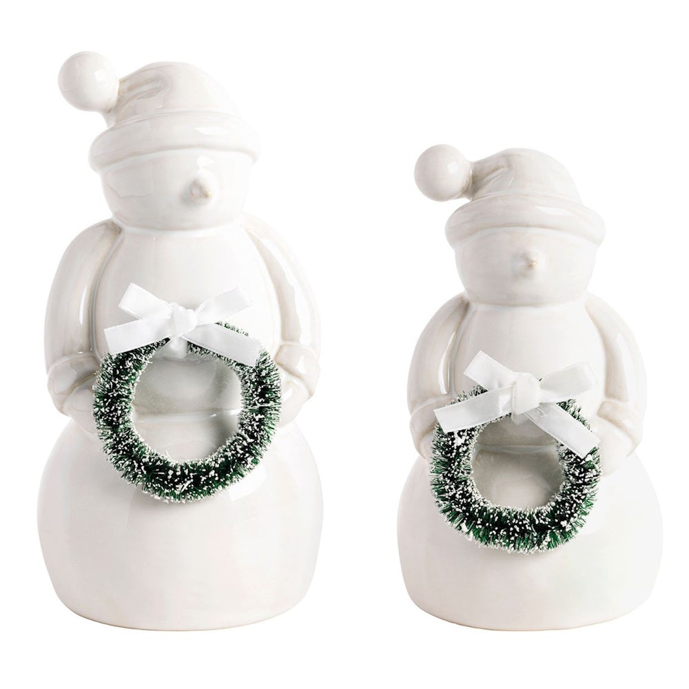 Two white ceramic snowman figurines wearing hats and holding miniature green wreaths with white bows.