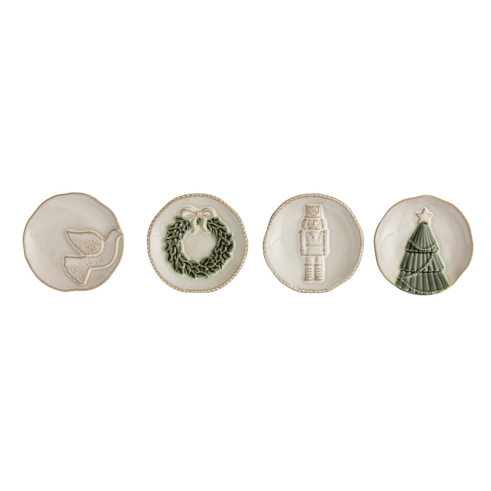 Set of four white ceramic tidbit plates featuring relief designs of a dove, wreath, nutcracker, and tree.