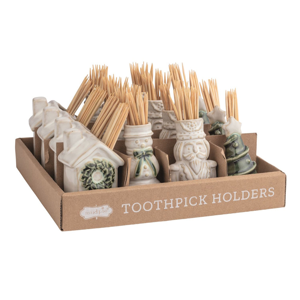 Display box of holiday ceramic toothpick holders shaped like houses, snowmen, nutcrackers, and trees.