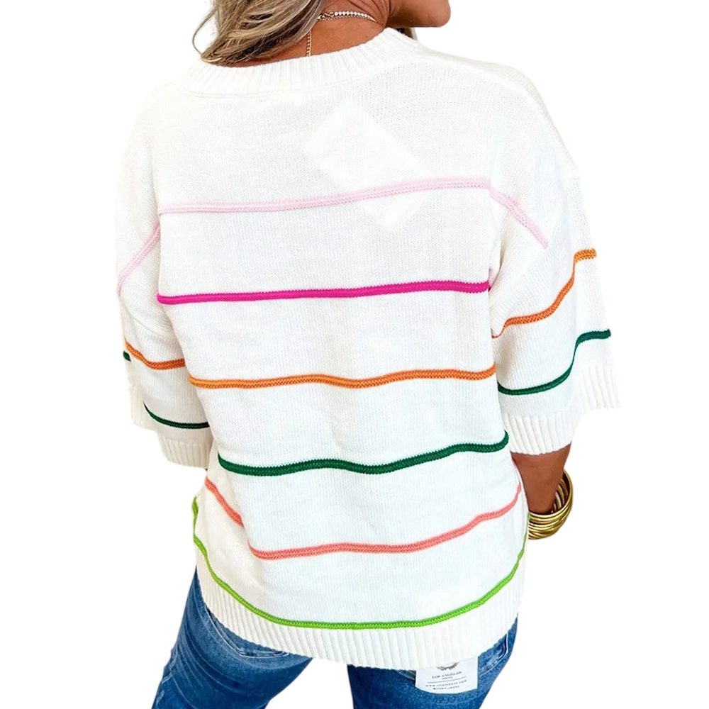 Back view of a person wearing a white, loose-knit sweater with colorful, thin horizontal stripes and blue jeans.