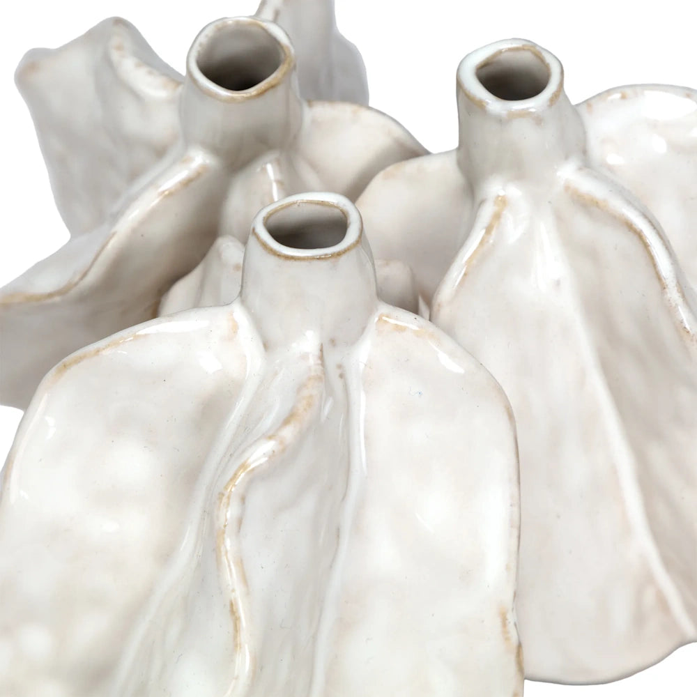 Close-up of a multi-spouted ceramic vase with wavy, leaf-like textures and a glossy white glaze.