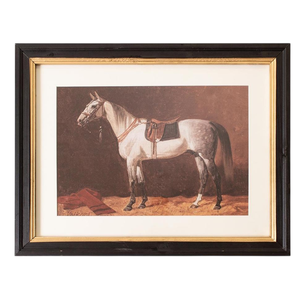 A framed painting of a saddled grey horse standing in a stable with a red blanket on the floor.