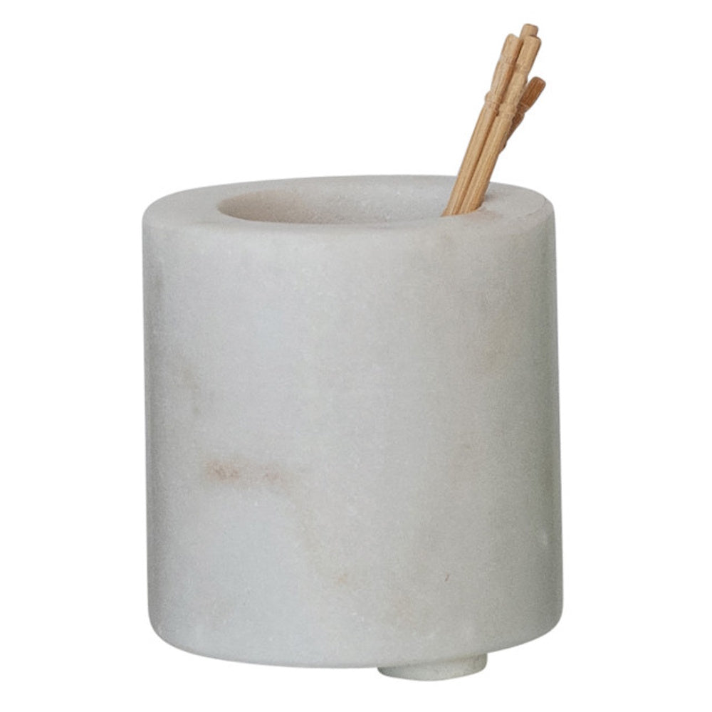 A cylindrical white marble toothpick holder containing a few wooden toothpicks on a plain background.