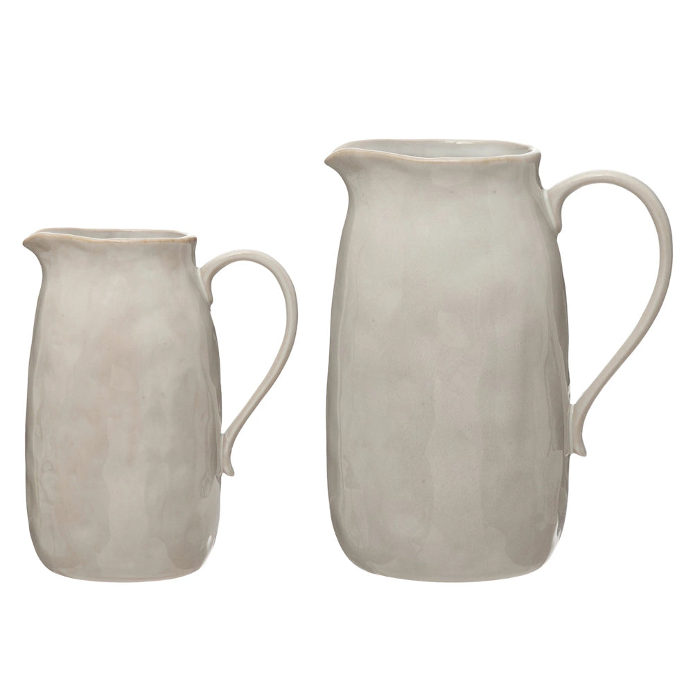 Two textured ceramic pitchers in off-white, shown in small and large sizes against a white background.