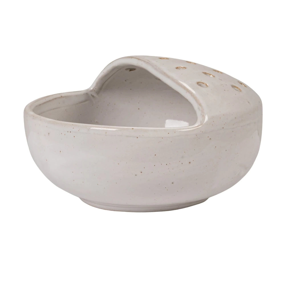 Speckled white stoneware strainer bowl with a built-in perforated drainage lid on a solid white background.