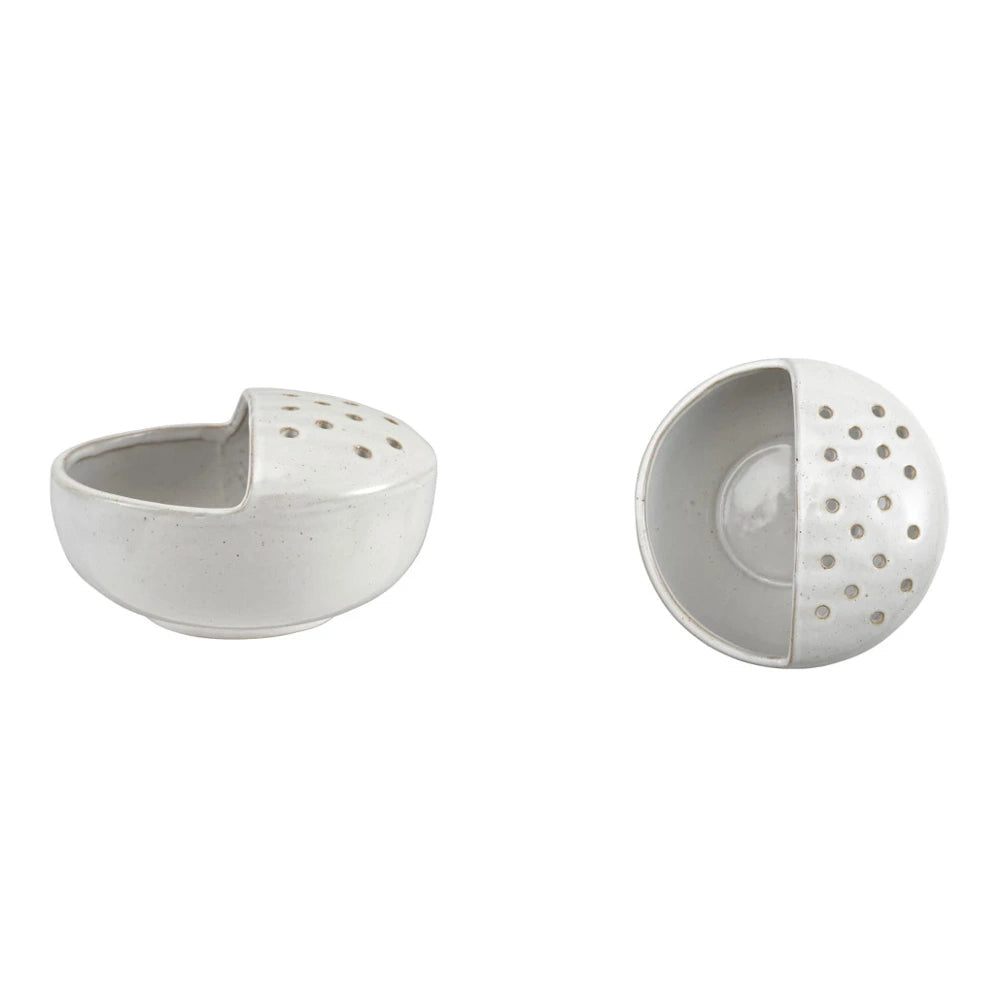 Two views of a white speckled stoneware berry strainer bowl with drainage holes on a white background.