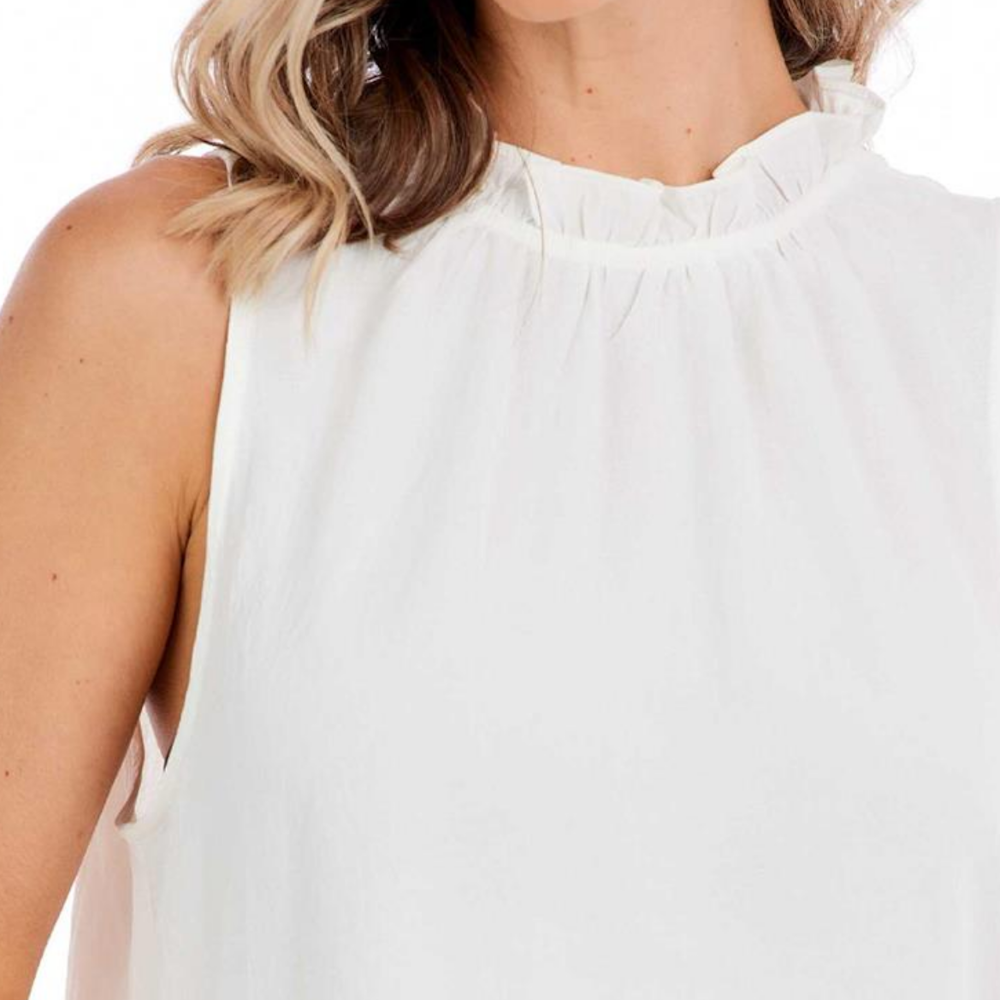 Close-up of a woman wearing a white sleeveless top with a ruffled high neckline.