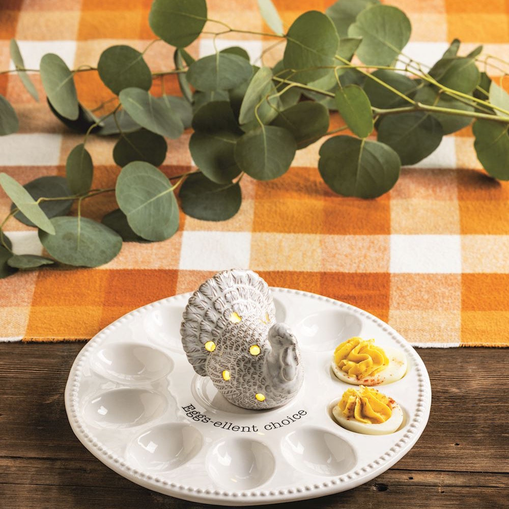 Ceramic turkey deviled egg platter with lights and "Eggs-ellent choice" text on a checkered mat.