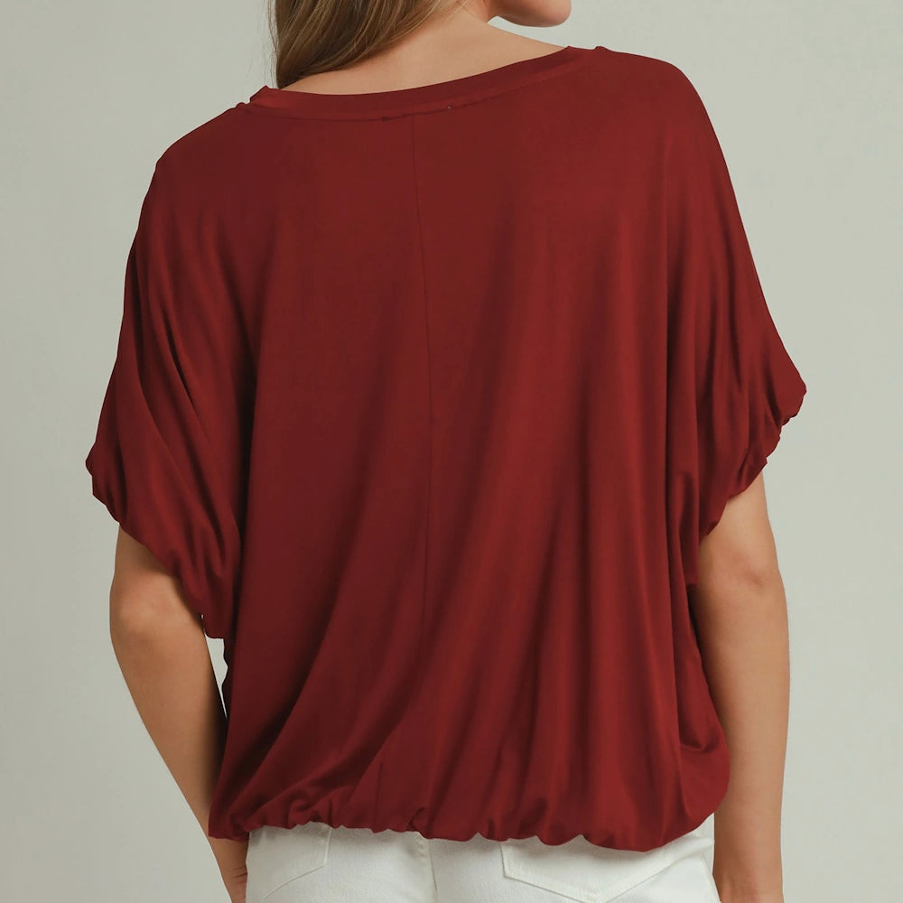 Back view of a person wearing a wine red loose-fit top with a bubble hemline and short batwing-style sleeves.