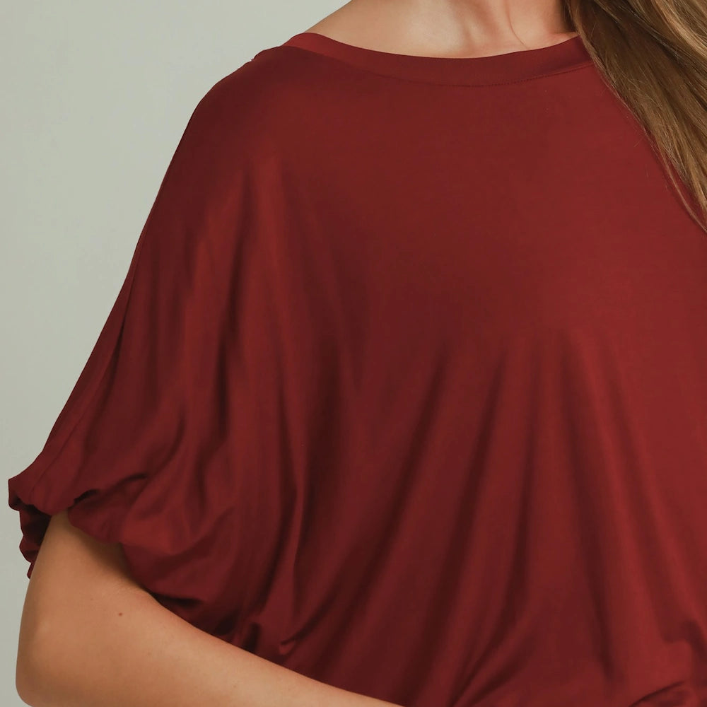 Close-up of a wine red top featuring a crew neckline and draped, short bubble sleeves.