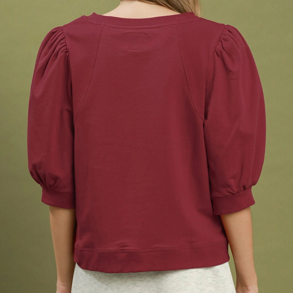 Back view of a person wearing a wine red pullover sweatshirt with volume puff elbow-length sleeves and ribbed hem.
