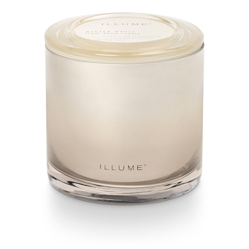 A reflective glass jar candle with its lid on and ILLUME branding on the front.