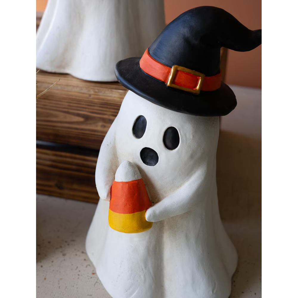 Ghost figurine wearing a witch hat and holding a piece of candy corn.