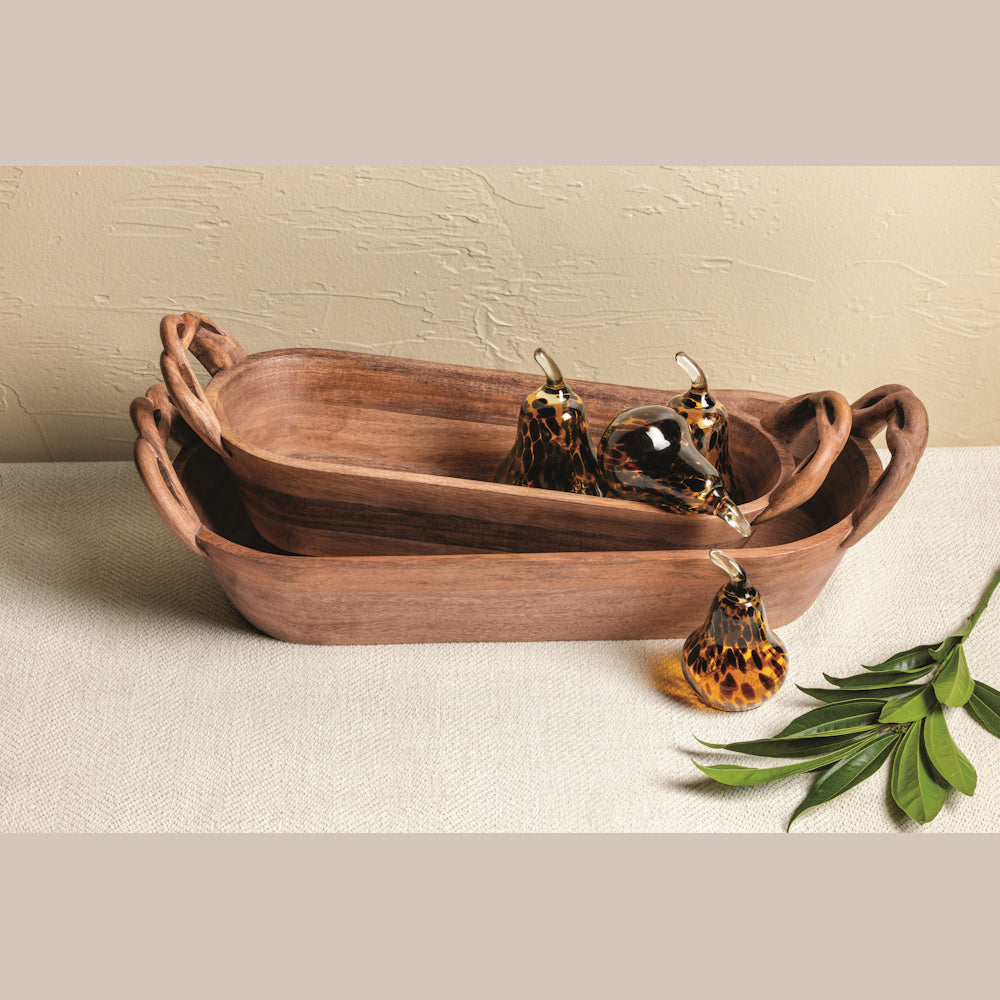 Two stacked wooden dough bowls with twisted handles, featuring decorative glass pears in a tortoiseshell pattern.