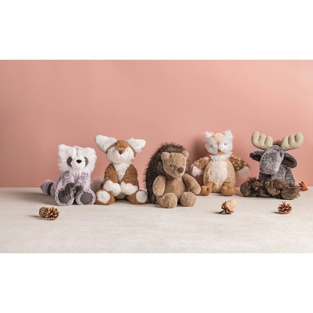 Five woodland animal plush toys lined up against a pink backdrop with pinecone accents.