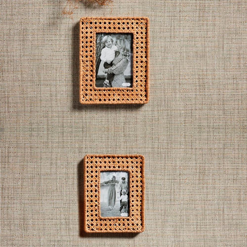 Two vertical woven cane picture frames with natural rattan texture hanging on a neutral fabric-textured wall.