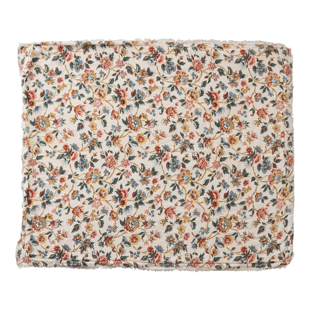 Vintage floral print throw with frayed edges in warm red, blue, and gold tones on a cream background.