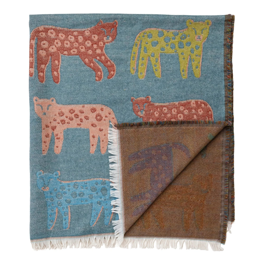 Folded teal woven throw blanket with colorful leopards, showing white fringe and a warm-toned back side.