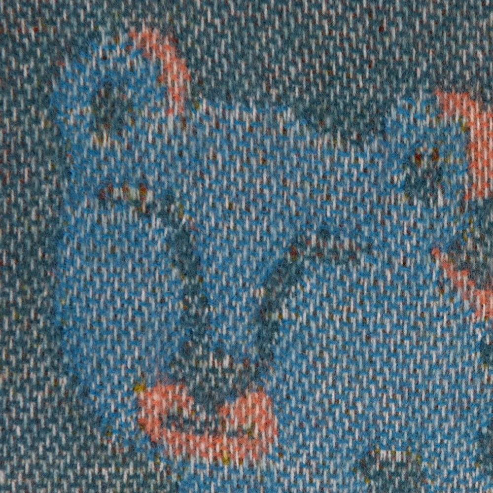 Macro shot showing the detailed woven jacquard fabric texture and colorful yarn threads of a throw blanket.