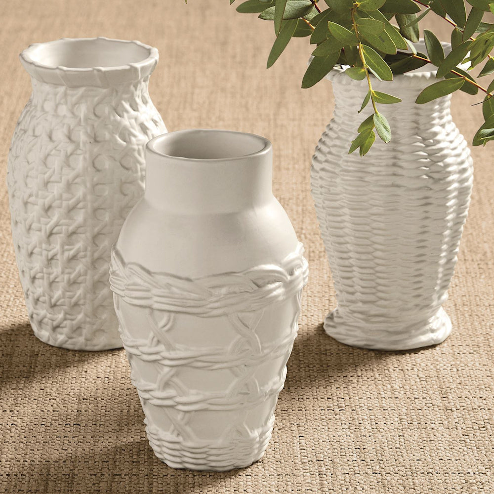 Three white woven stoneware bud vases with various basket-weave textures on a beige burlap surface.
