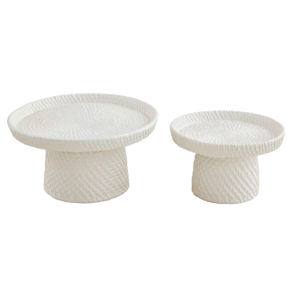 Two white woven stoneware pedestal servers in different sizes, featuring a textured wicker pattern on a plain background.