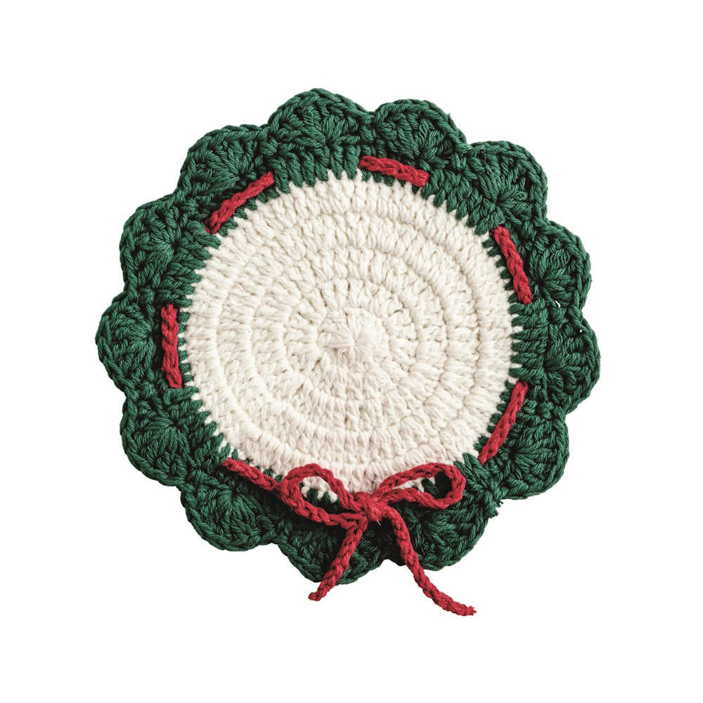 Scalloped round crochet Christmas trivet featuring a white center with a green wreath border and a red bow.