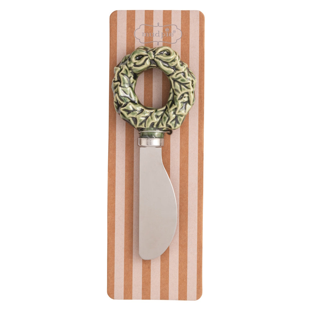 Green Christmas wreath figural spreader with a bow on striped packaging.