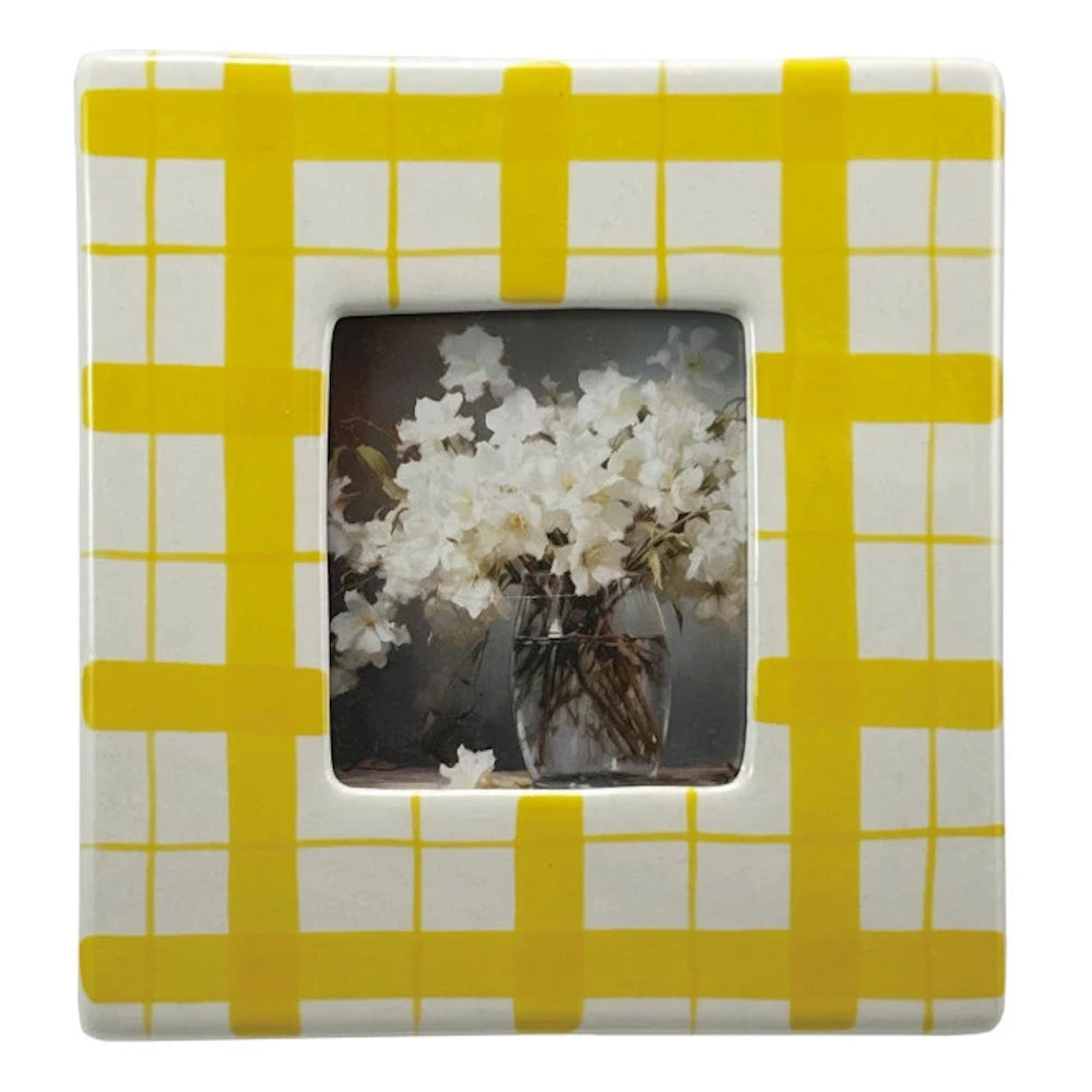 Yellow and white checkered ceramic picture frame featuring a photo of white flowers in a glass vase.
